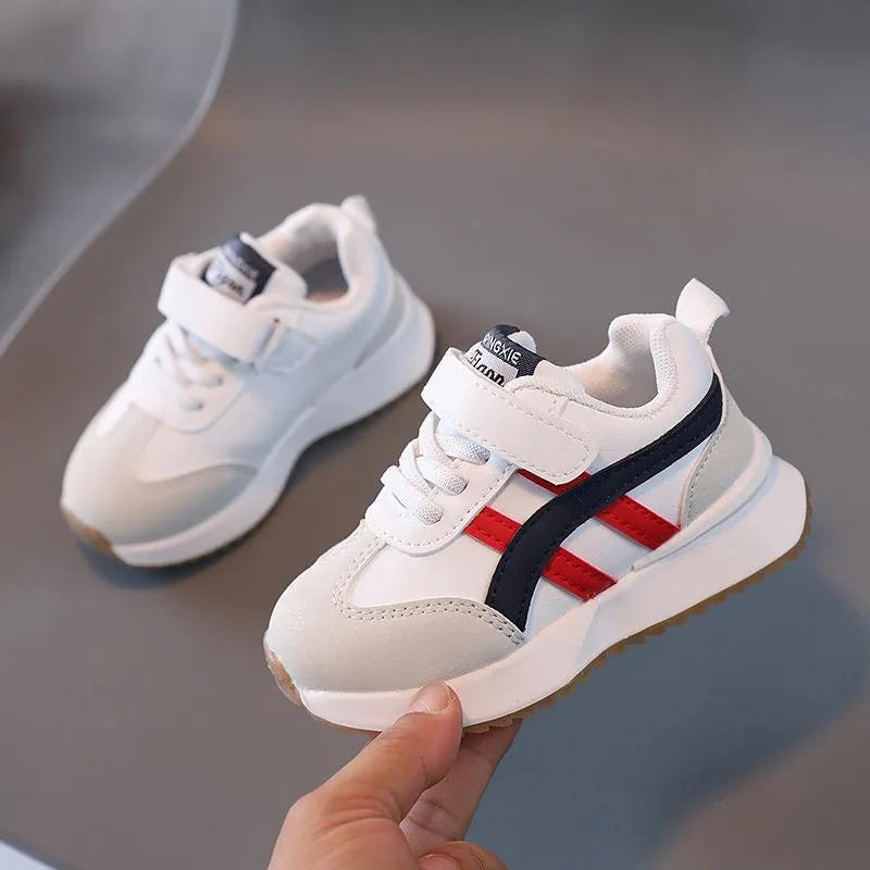 Children's white synthetic leather sneaker with Velcro strap and non-slip rubber sole.