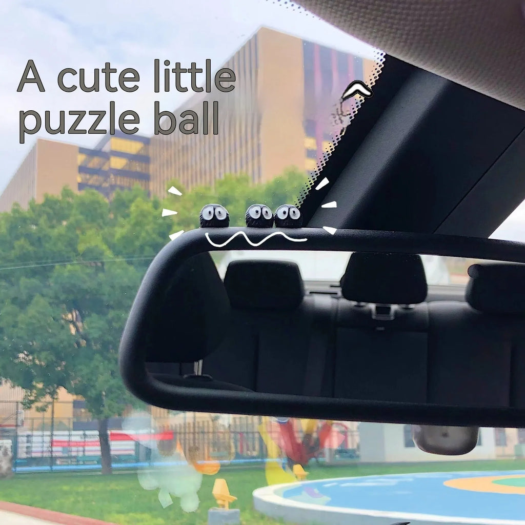 Small black cartoon-styled resin briquette car decoration ornament with traceless glue tape on a surface.