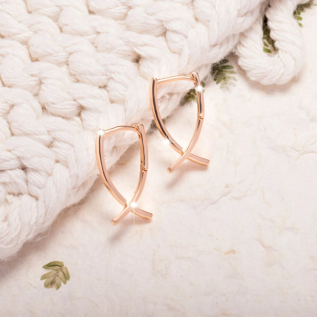 Rose gold cross shaped earrings with metallic finish and pendant design