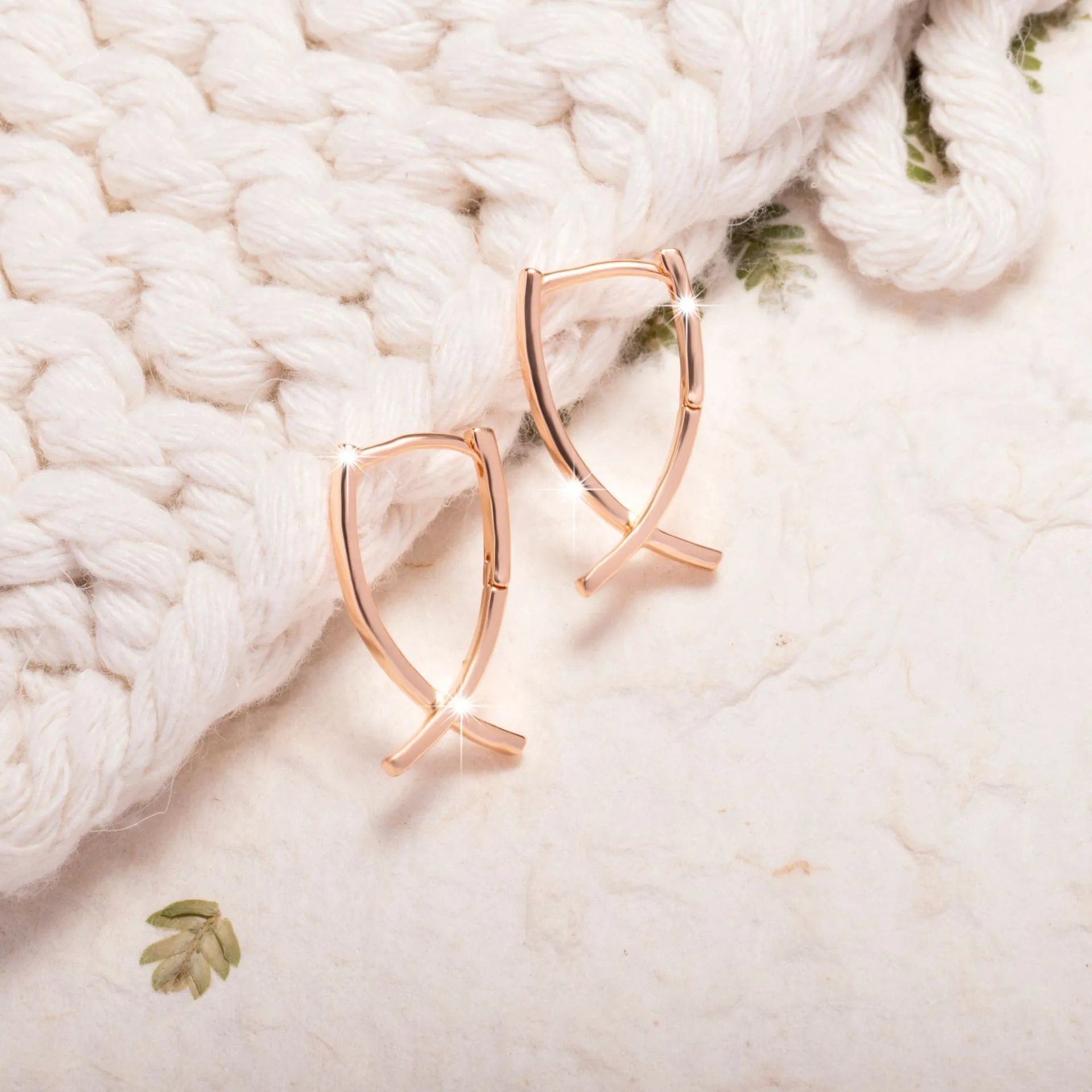 Rose gold cross shaped earrings with metallic finish and pendant design