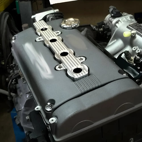 Aluminium alloy engine harness housing bracket in blue, red, and silver, showing versions with and without mounting holes.