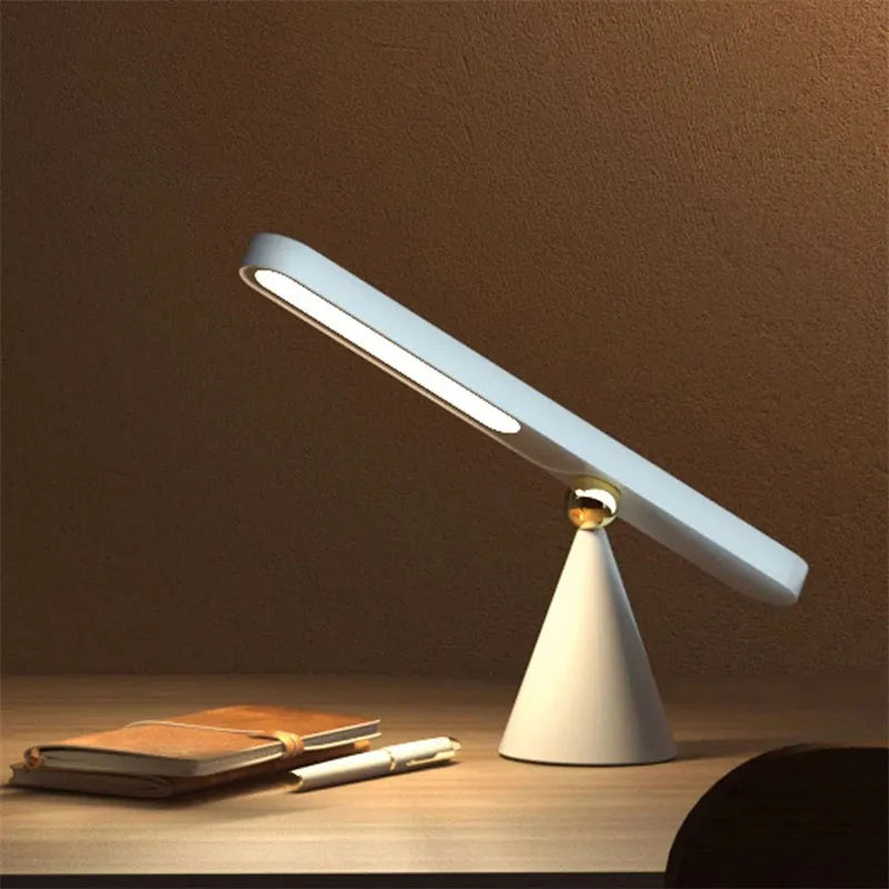 White geometric desk lamp with USB cable and magnetic base for wall mounting.