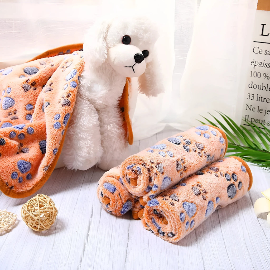 Cloth dog blanket with paw print design in beige, shown in a large size on a sofa.