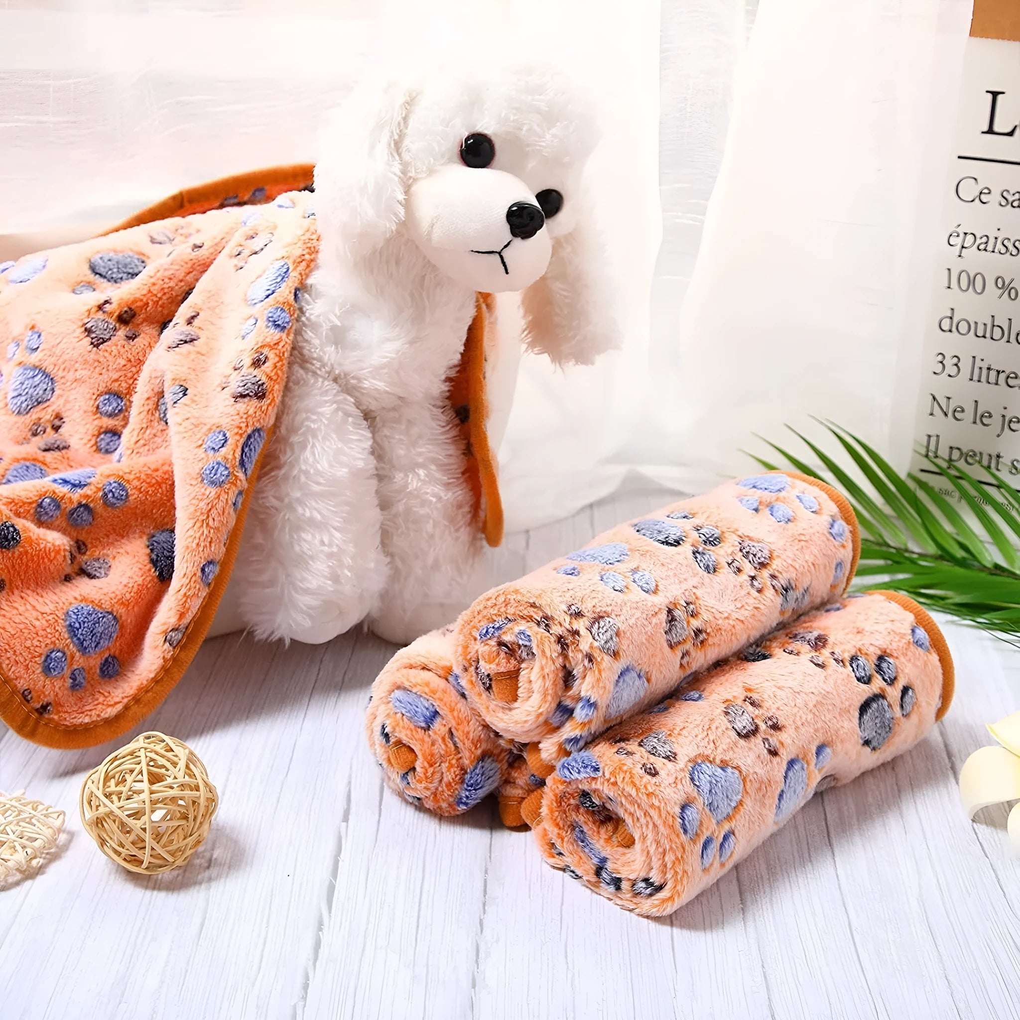 Cloth dog blanket with paw print design in beige, shown in a large size on a sofa.