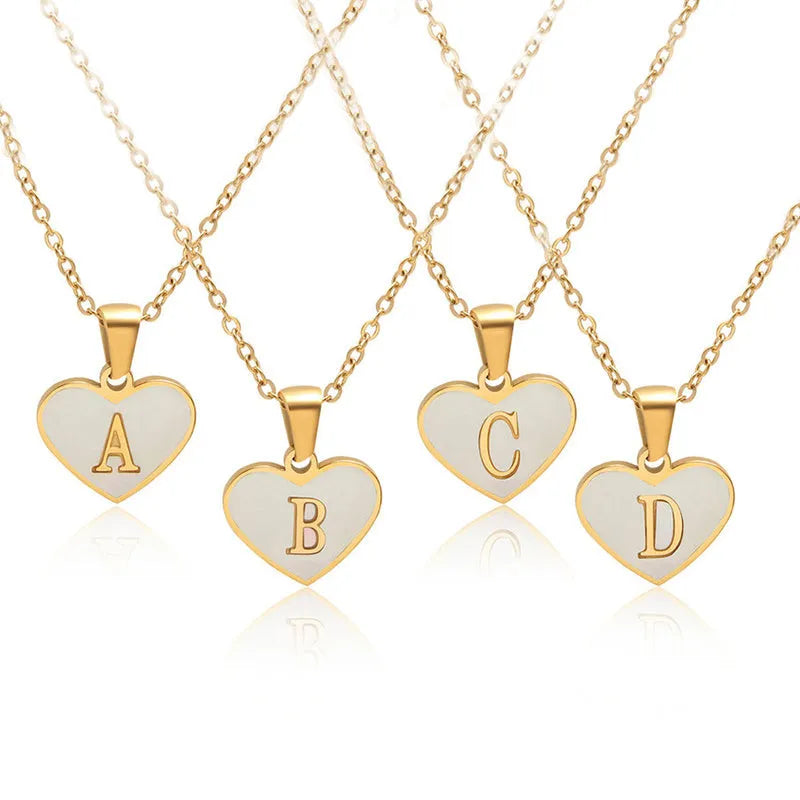 Gold chain necklace with white shell heart pendant featuring single letter customisation option