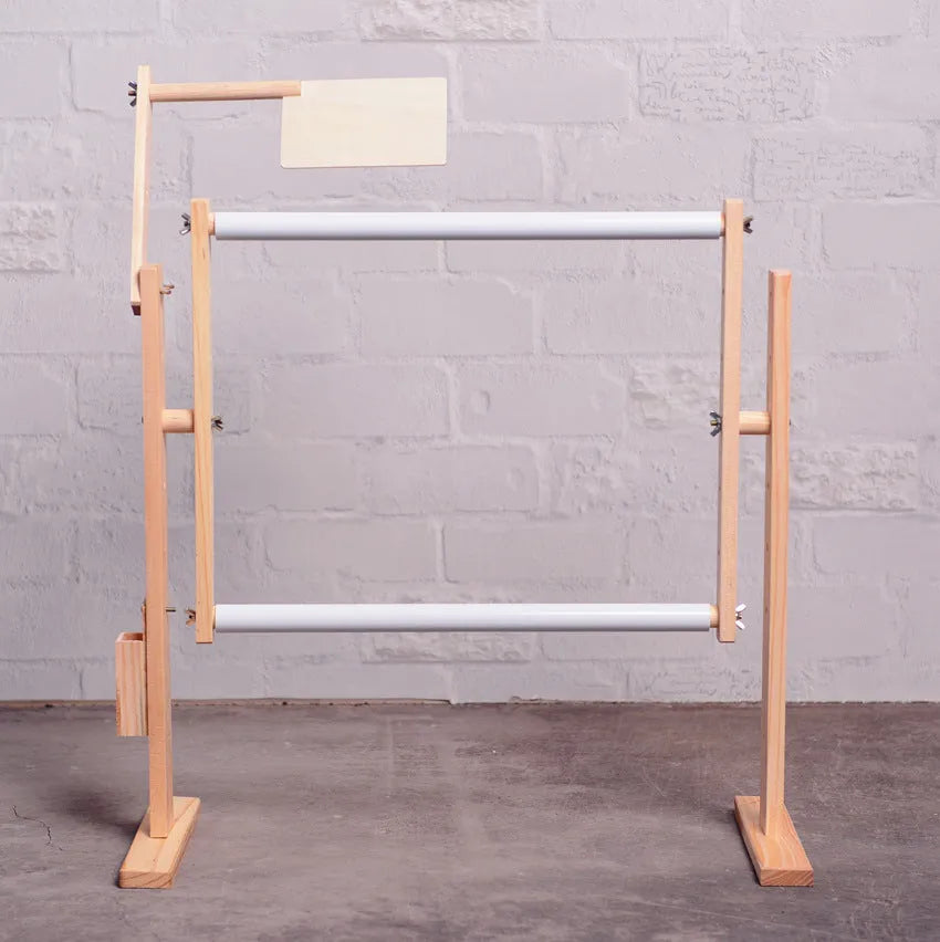 Vertical solid wood cross stitch frame on a desktop, showing adjustable height and pine construction.