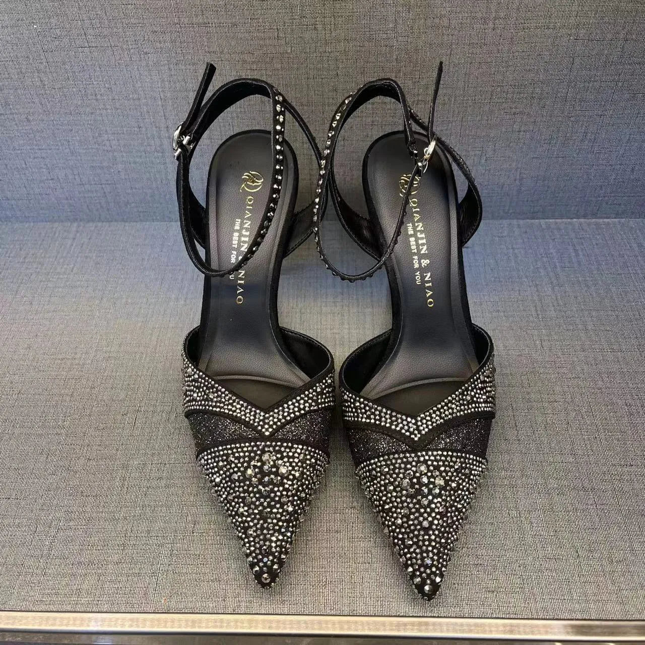Women's black hollow cut stiletto high heels with pointed toe and red sole on a white background