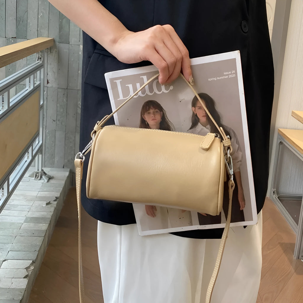 Vegetable-tanned leather cylindrical crossbody phone bag in black colour showing adjustable strap and visible stitching