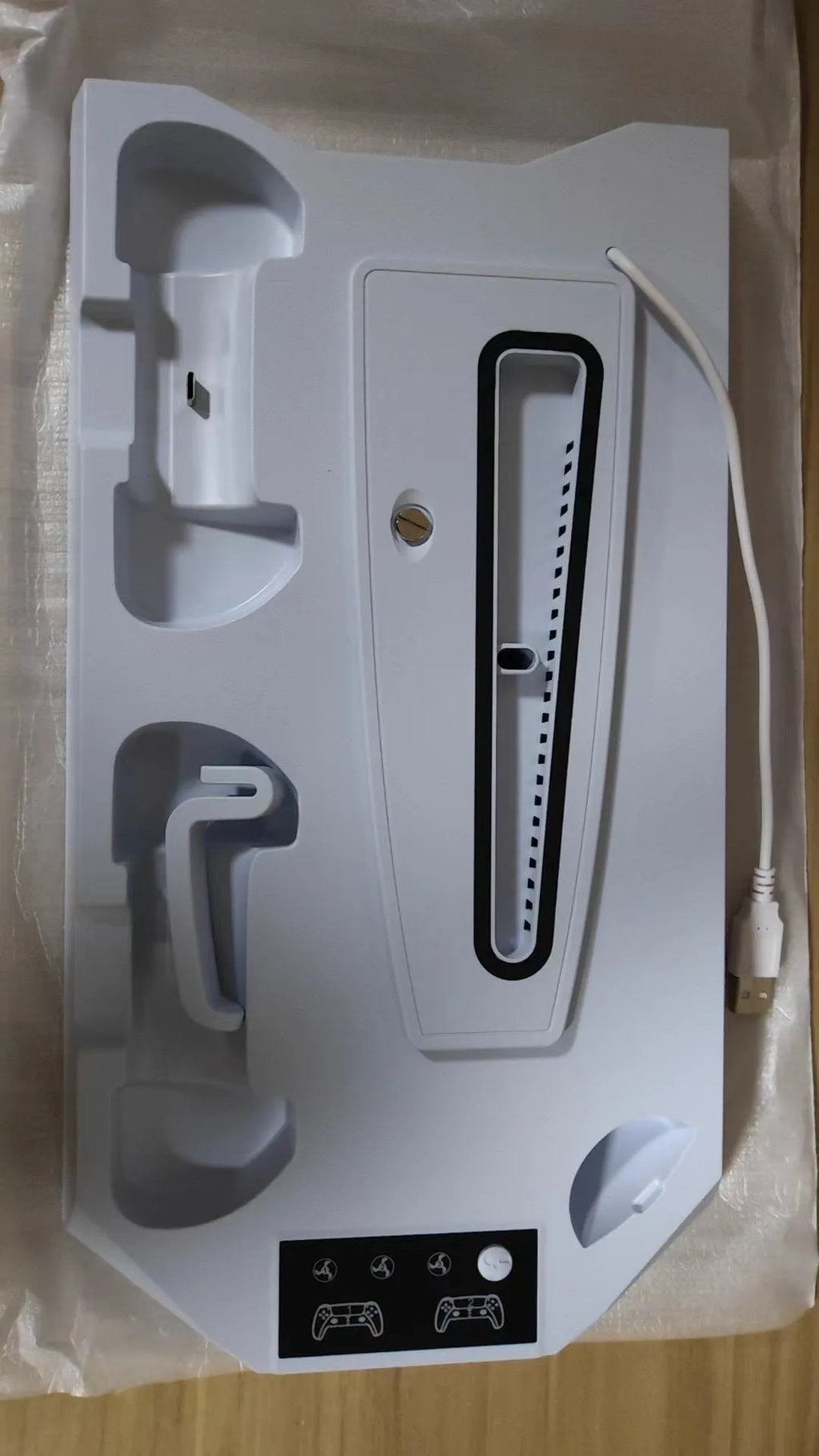 Black PS5 charging base radiator dock with a DualSense controller plugged in and a headset hanging on the hook.
