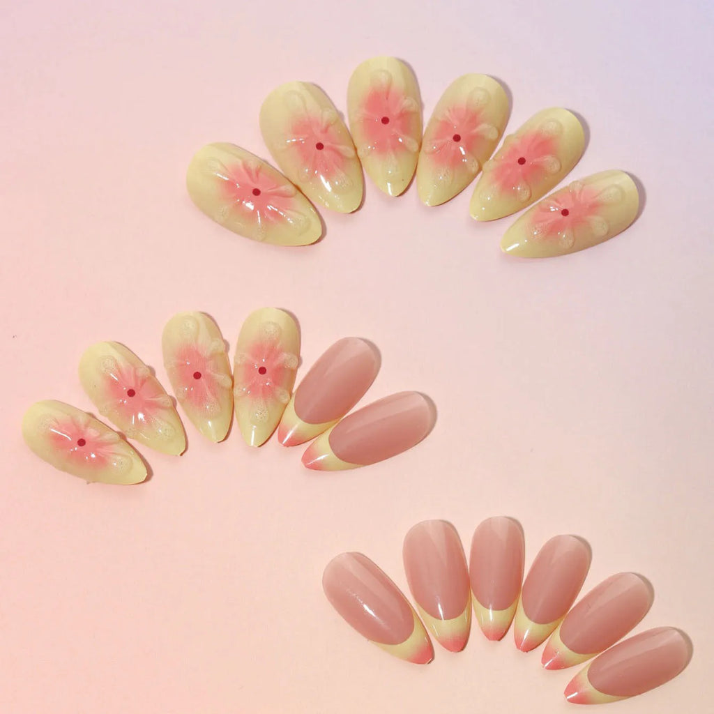 Plastic false nails with white cartoon 3D flower decoration, pot of jelly glue, and nail file on pink background.