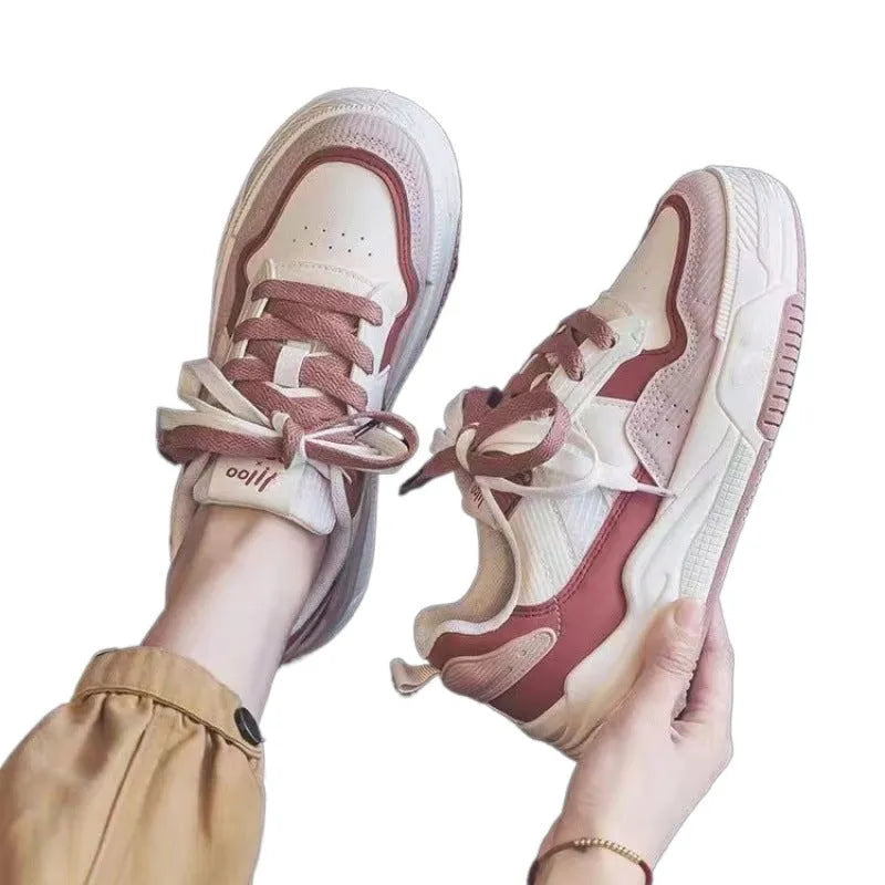Pink and white low-top height-increasing sneakers with rubber soles on a plain background.