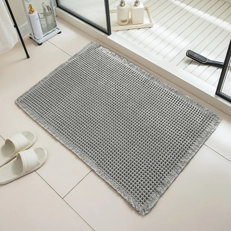 Square checkered polyester bathroom carpet on a tiled floor in a light grey colour.