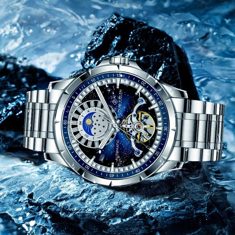 Men's silver automatic mechanical watch with blue dial, stainless steel strap, and transparent case back showing movement