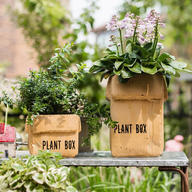 Cement flower pot with brown paper box texture and drainage holes, shown in a neutral home setting.