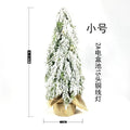 Small 24-inch white artificial Christmas tree with built-in LED lights and simulated snow sprayer on a desktop.