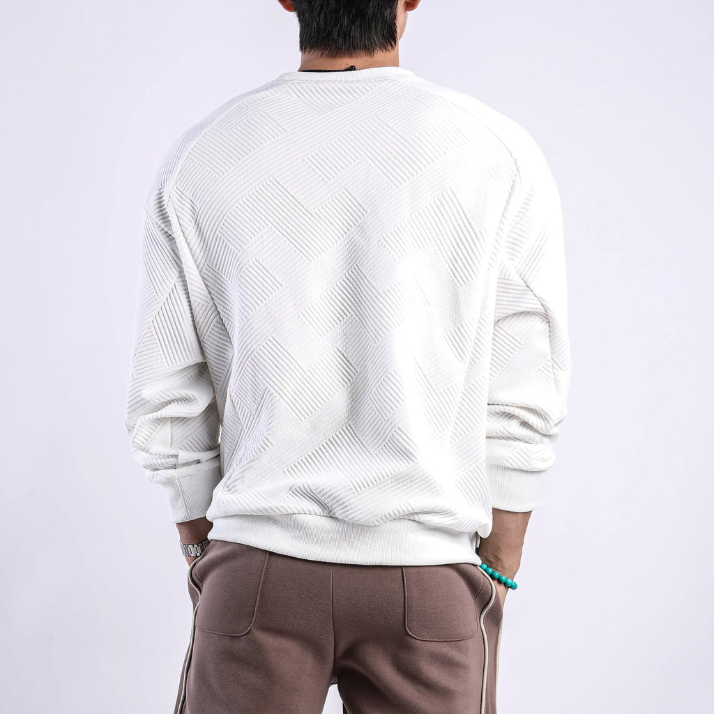 Man wearing a loose-fit, long-sleeved twill jacquard sweater in a solid colour with a round neck.