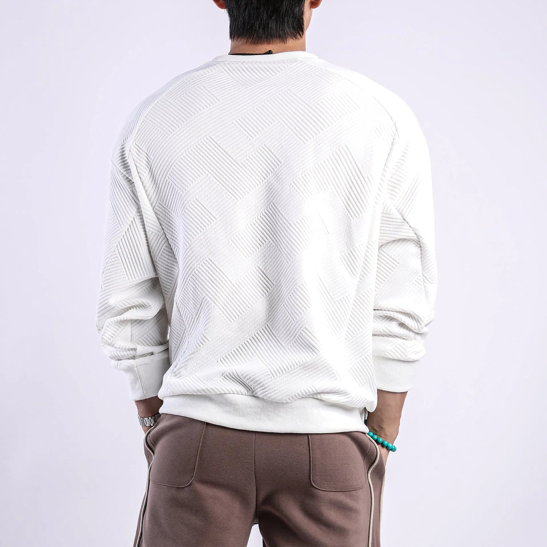 Man wearing a loose-fit, long-sleeved twill jacquard sweater in a solid colour with a round neck.