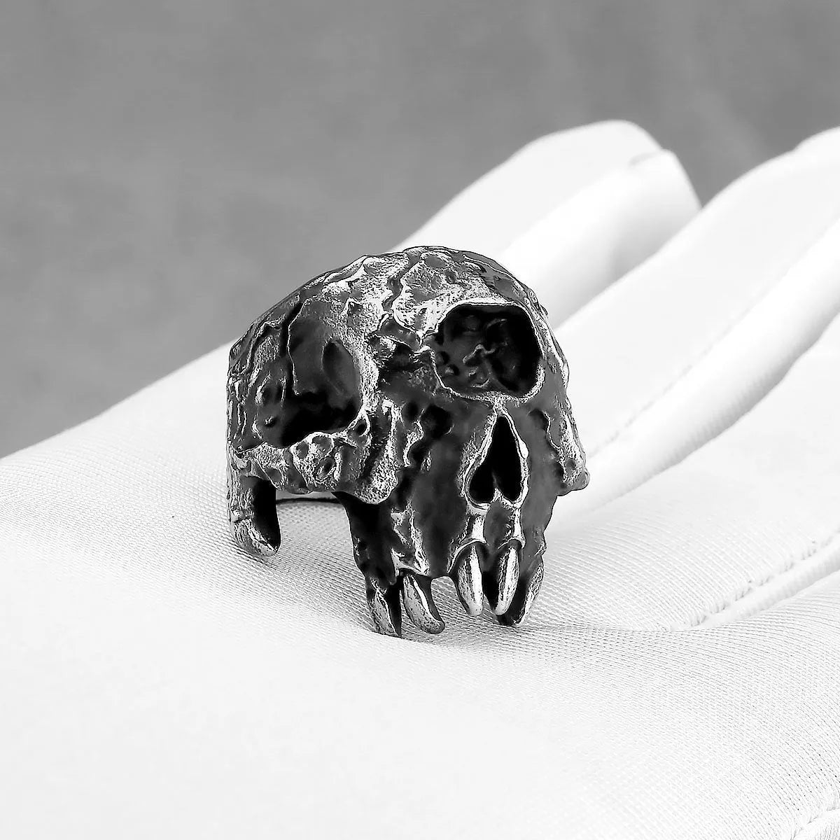 Close-up of a retro alloy ring with a detailed one-eyed skull design on a dark background.