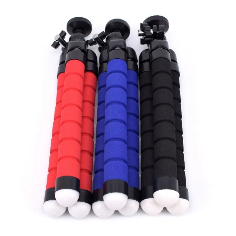 Black flexible octopus tripod with bendable legs wrapped around a pole next to a smartphone.