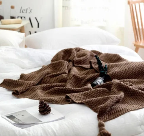 Nordic fringed knit ball acrylic blanket in beige, measuring 130 by 170 cm on a sofa.