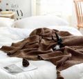 Nordic fringed knit ball acrylic blanket in beige, measuring 130 by 170 cm on a sofa.