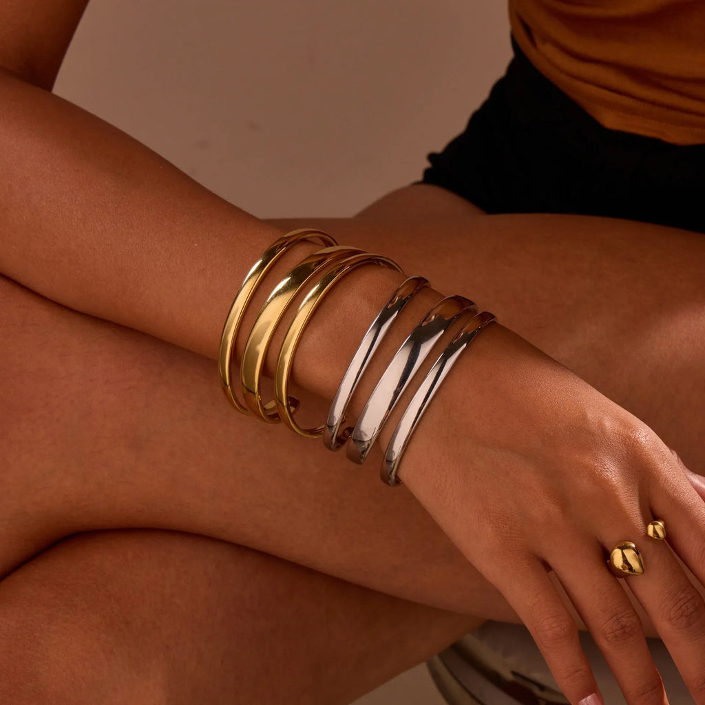 Women's stainless steel bracelet with geometric line design, shown in gold and steel finish options.