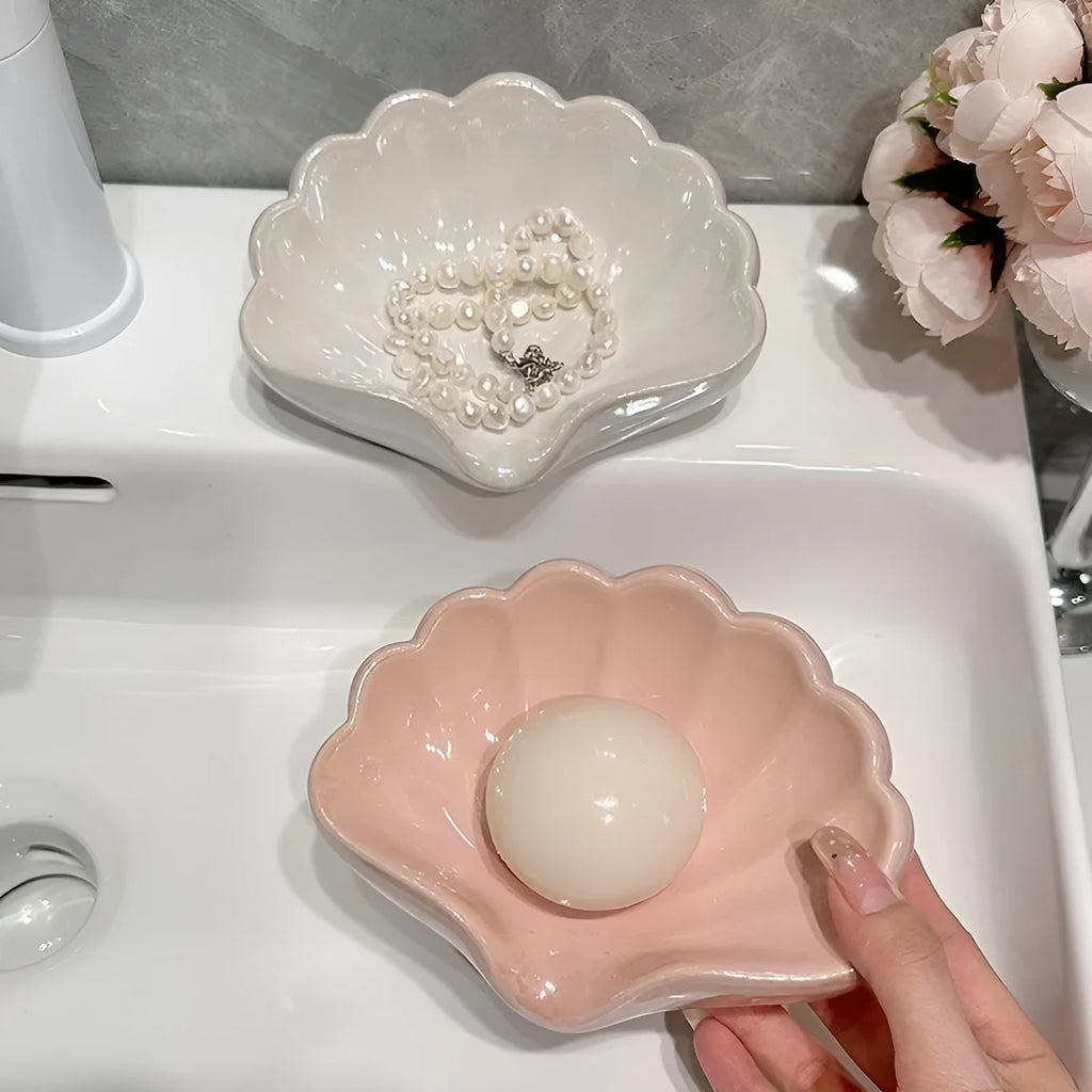 White or pink plastic shell-shaped soap dish for bathroom countertops.