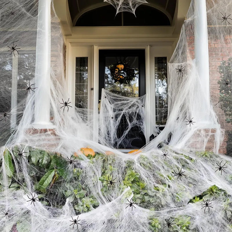 White cotton spider web Halloween decoration bundle with plastic spiders scattered on a dark background.