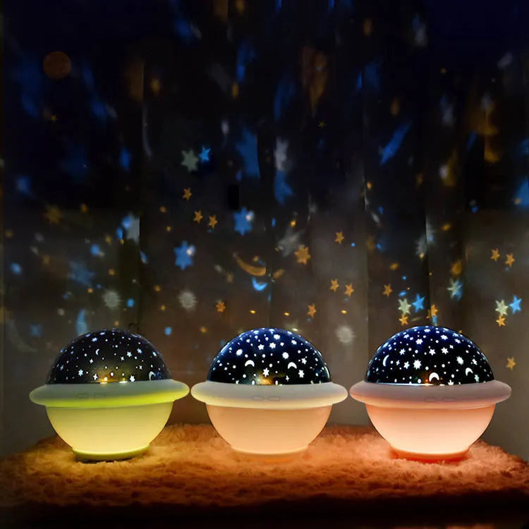 Pink UFO-shaped plastic LED night light projecting a starry sky pattern on a wall.