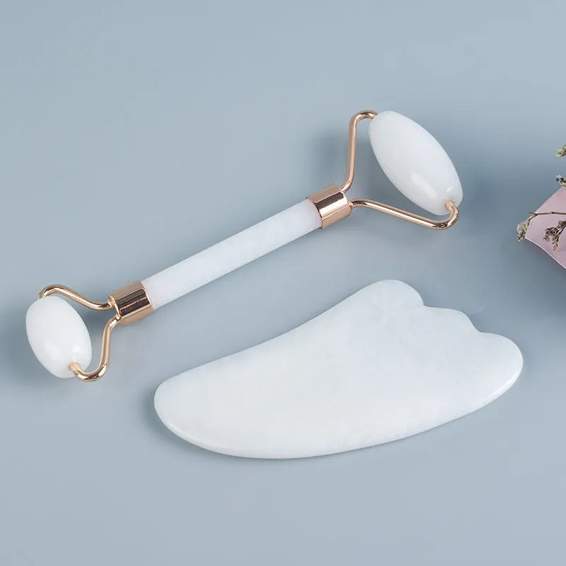 Natural white jade double-headed facial roller and matching scraping board set on a flat surface.