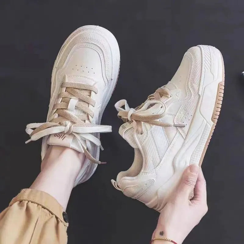 Pink and white low-top height-increasing sneakers with rubber soles on a plain background.