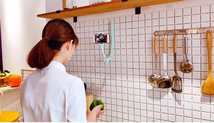 Black flexible arm phone holder with suction cup base bent into an S-shape, holding a mobile phone.