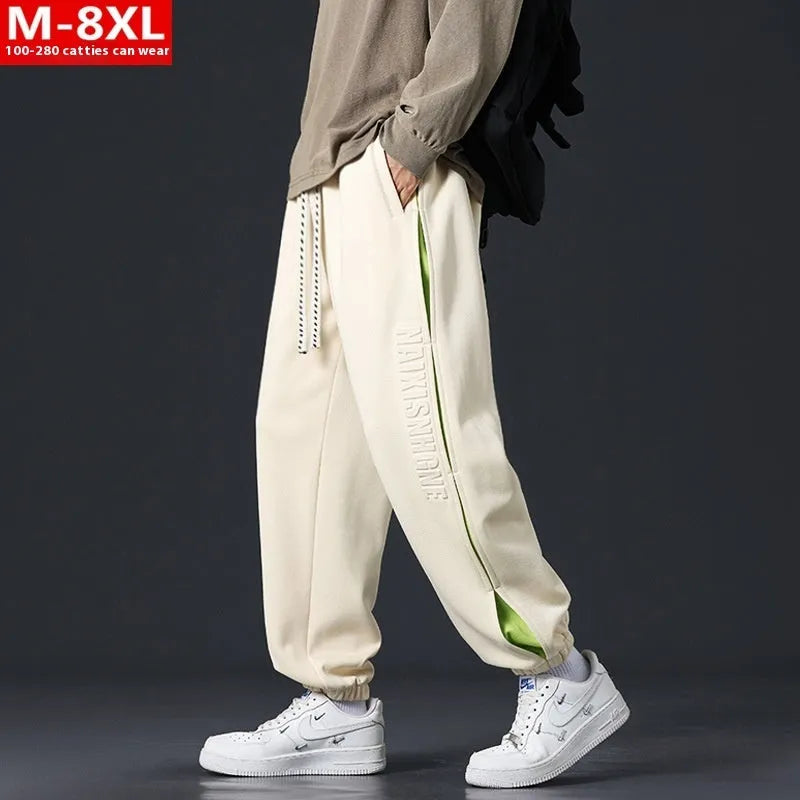Man wearing grey green loose-fit cotton trousers with elastic ankle bands and visible stitch detailing.