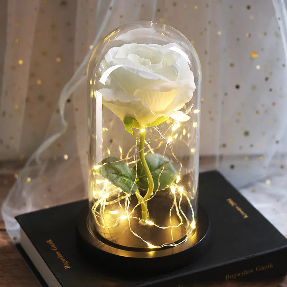 LED silk rose bouquet with glass lampshade glowing with warm white light on a solid wood base.