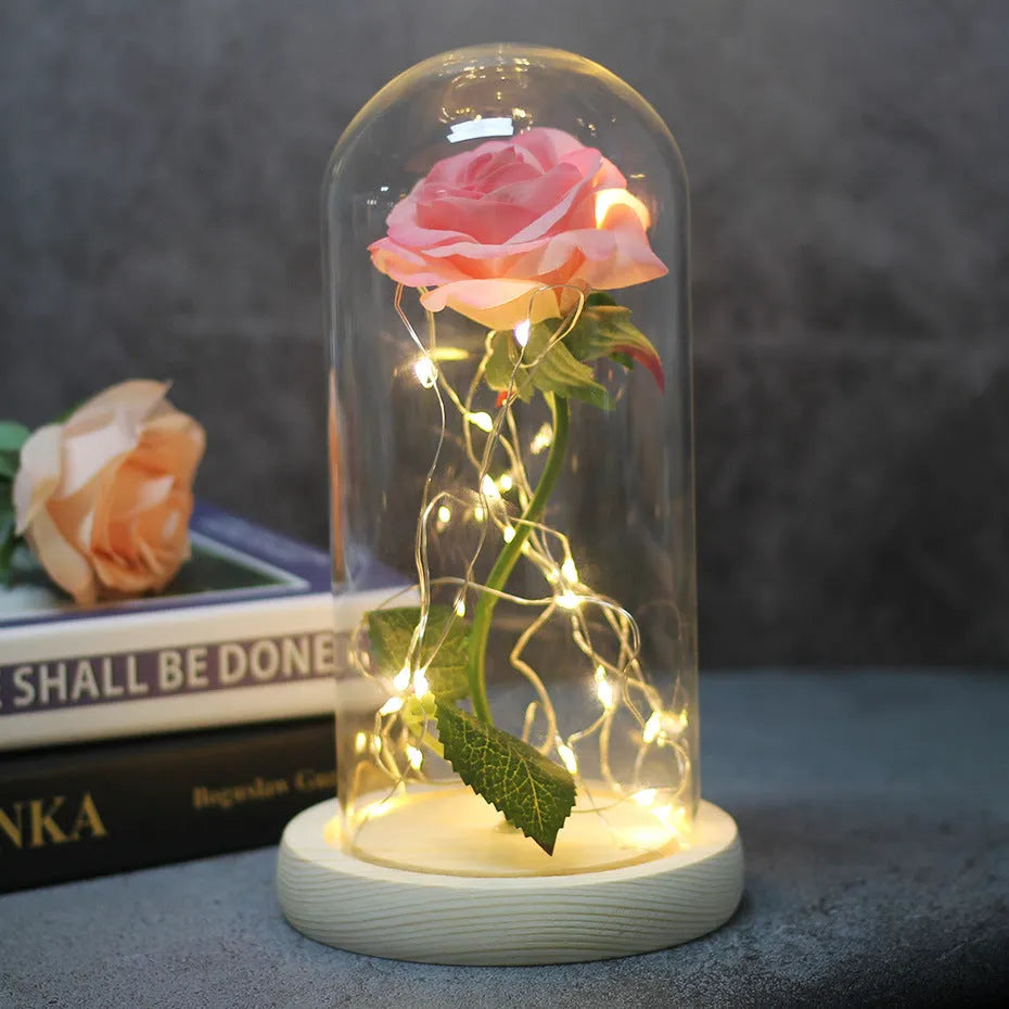 LED silk rose bouquet with glass lampshade glowing with warm white light on a solid wood base.