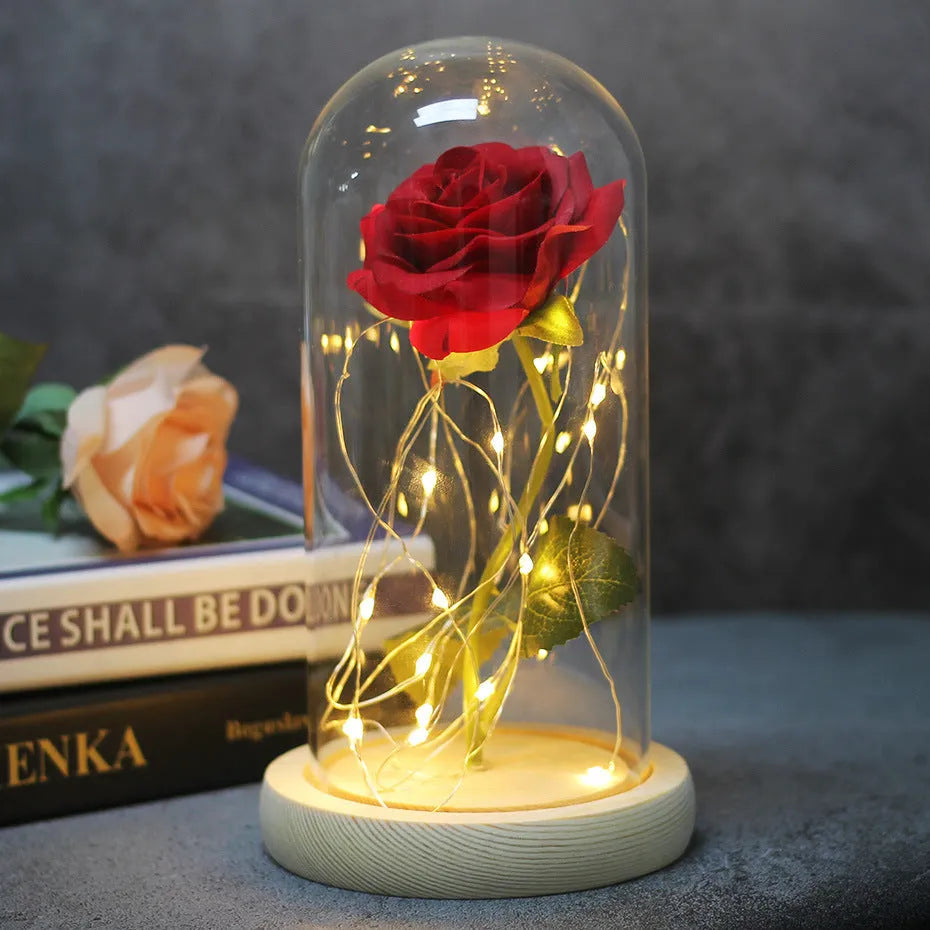 LED silk rose bouquet with glass lampshade glowing with warm white light on a solid wood base.