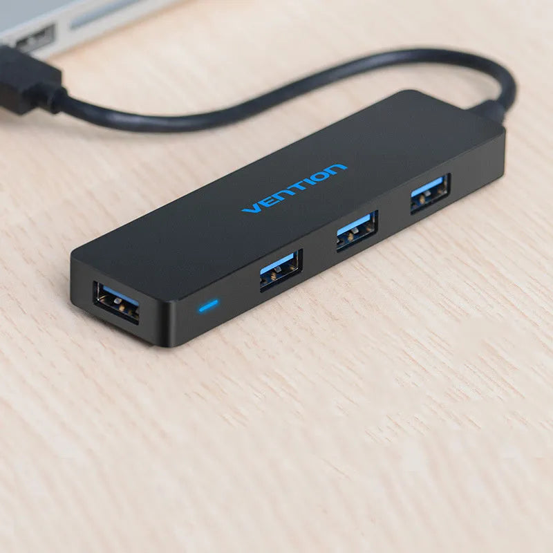 Black four-port USB 3.0 hub with a short 0.15m cable connected to a laptop