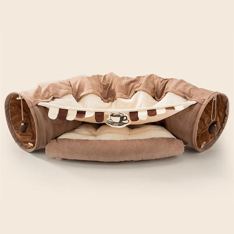 Collapsible cloth cat tunnel folded flat next to a cat, showing Coffee colour option.