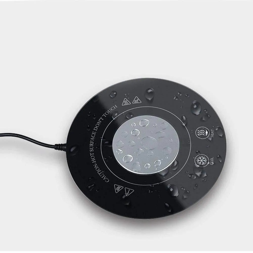 Black USB-powered hot and cold coaster for drinks on a desk next to a coffee cup.