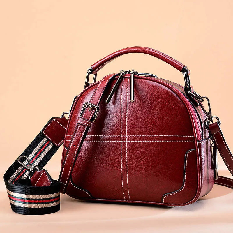 Round leather handbag with soft handle and zipper opening in wine red colour