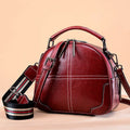 Round leather handbag with soft handle and zipper opening in wine red colour