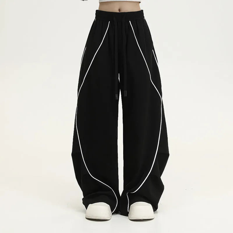 Black and white striped pleated wide-leg hip hop sports pants on a mannequin, showing loose fit and mid waist.