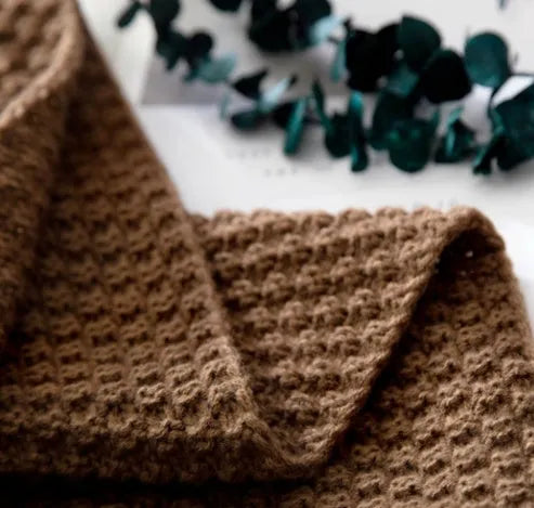 Nordic fringed knit ball acrylic blanket in beige, measuring 130 by 170 cm on a sofa.
