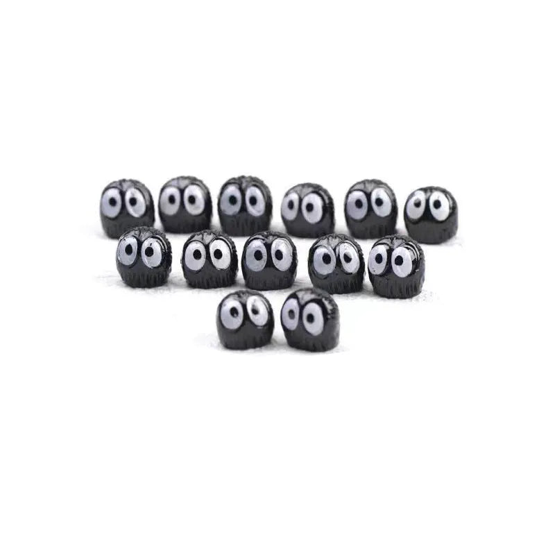 Small black cartoon-styled resin briquette car decoration ornament with traceless glue tape on a surface.