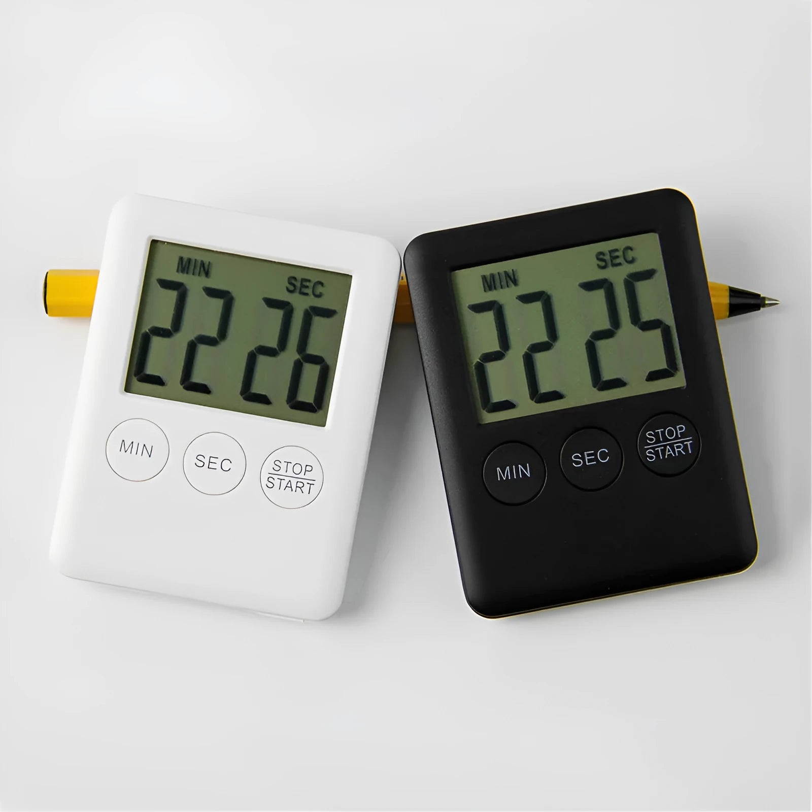 Black and white digital kitchen timer with magnetic back on a refrigerator.