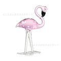 Clear crystal flamingo decorative sculpture with pink dots on a table.