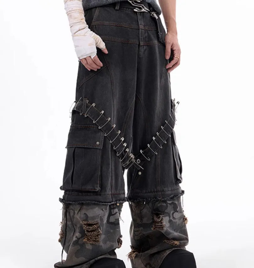 Grey men's jeans with camouflage pattern splicing and silver pin and black ribbon detailing on the legs.