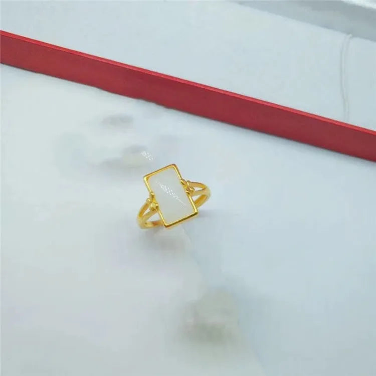 Adjustable brass gold-plated ring with a long black gemstone inlay on a finger.