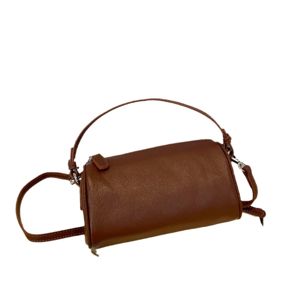 Vegetable-tanned leather cylindrical crossbody phone bag in black colour showing adjustable strap and visible stitching