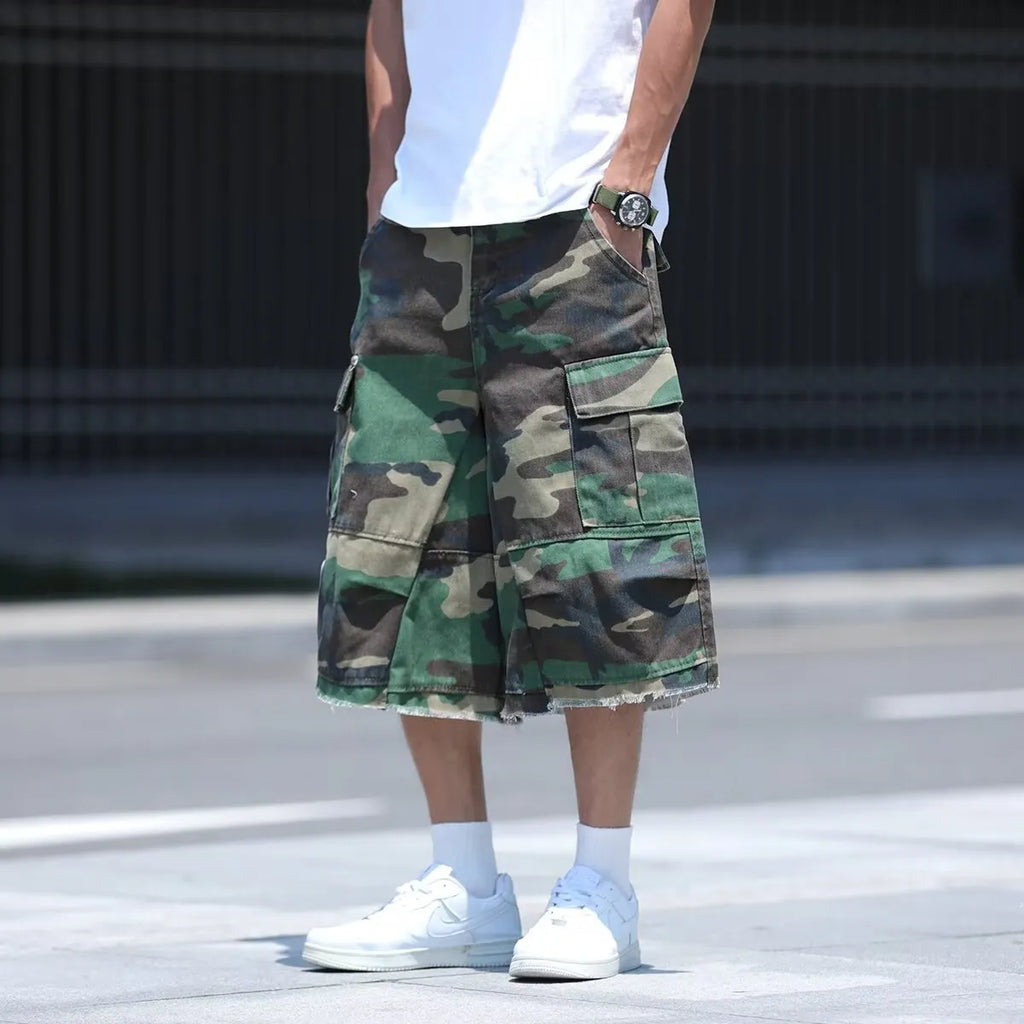 Man modelling loose-fit camouflage shorts in a retro workwear style for summer.